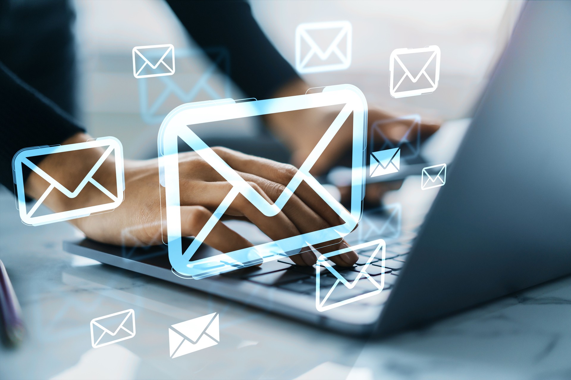 Hands typing on laptop with floating digital email icons symbolizing online communication and cloud-based messaging services in business context.